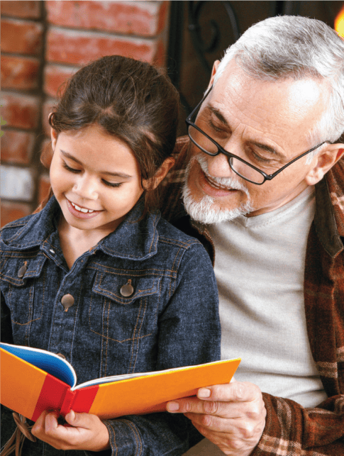 Grandfather reading a book to his granddaughter.